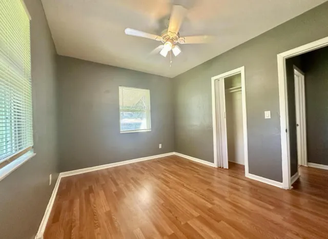 a view of an empty room with wooden floor and a window