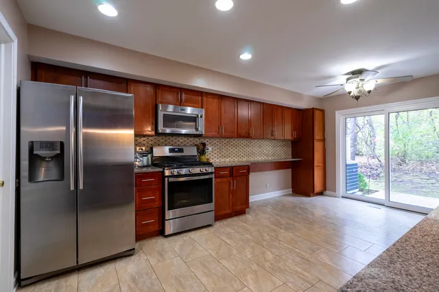 a kitchen with stainless steel appliances granite countertop a refrigerator a sink and a stove