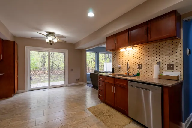 a room with kitchen island granite countertop wooden cabinets a sink and a window