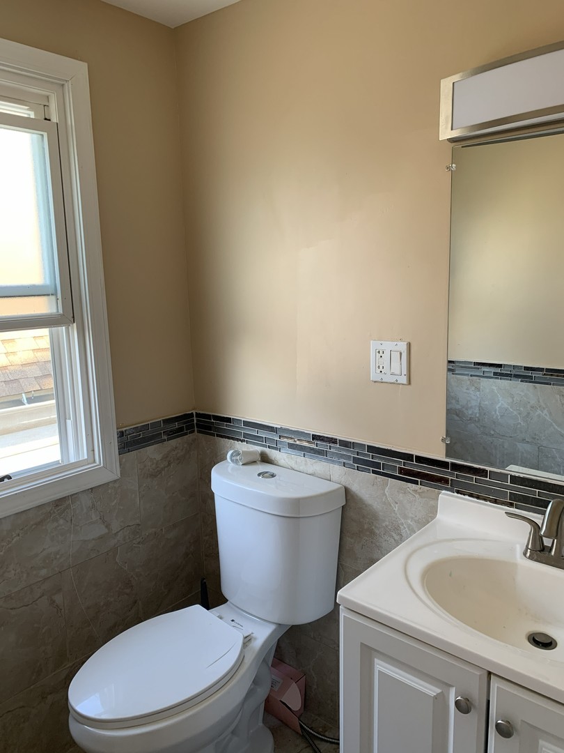 10529 South Perry Avenue Chicago, IL 60628 - Photo 14 of 17 a bathroom with a sink mirror toilet and window