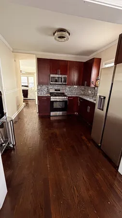 a kitchen with stainless steel appliances kitchen island granite countertop a stove a refrigerator a sink a dining table and chairs with wooden floor