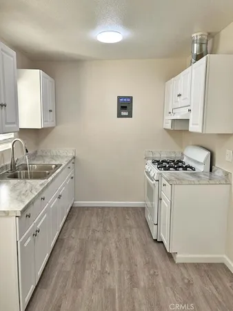 a kitchen with granite countertop a sink stove and cabinets