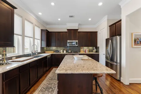 a kitchen with stainless steel appliances granite countertop a refrigerator a sink a stove a microwave and wooden cabinets