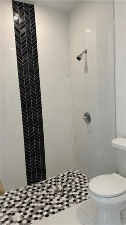 a bathroom with a toilet a shower and a black stove