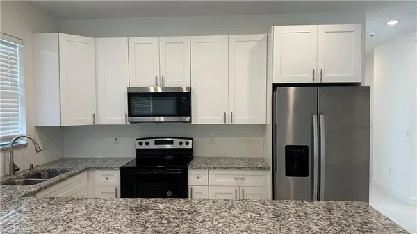 a kitchen with granite countertop a refrigerator and a stove top oven