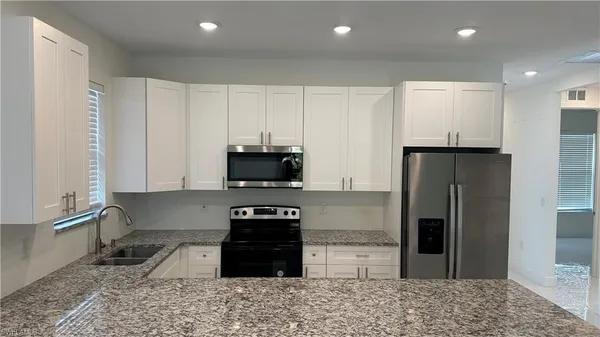 a kitchen with stainless steel appliances granite countertop a refrigerator a stove a sink and a microwave