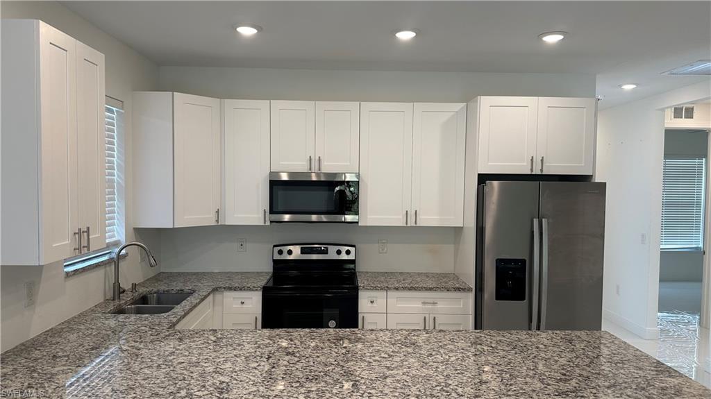 5901 Rita Avenue North Lehigh Acres, FL 33971 - Photo 7 of 22 a kitchen with stainless steel appliances granite countertop a refrigerator a stove a sink and a microwave