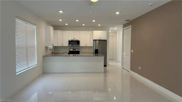 a large white kitchen with kitchen island a sink stainless steel appliances and cabinets
