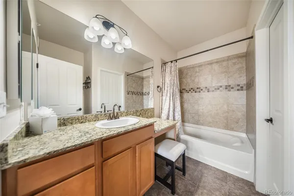 a bathroom with a granite countertop sink a toilet a mirror and shower