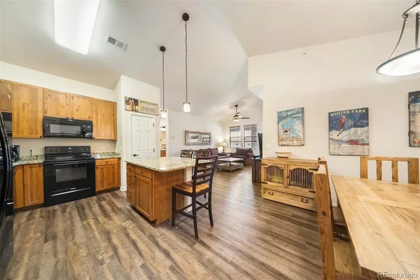 a kitchen with stainless steel appliances a stove a sink a oven a dining table and chairs with wooden floor