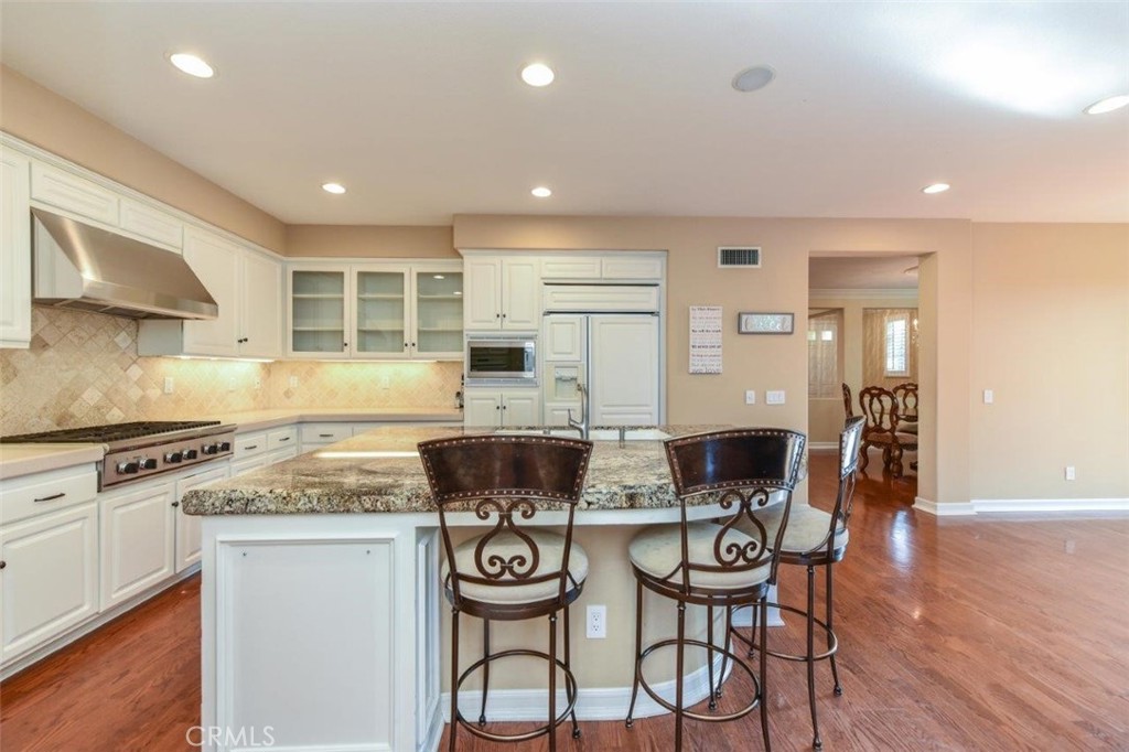 3 Plumbago Irvine, CA 92620 - Photo 17 of 51 a kitchen with stainless steel appliances granite countertop a stove top oven a dining table and chairs with wooden floor