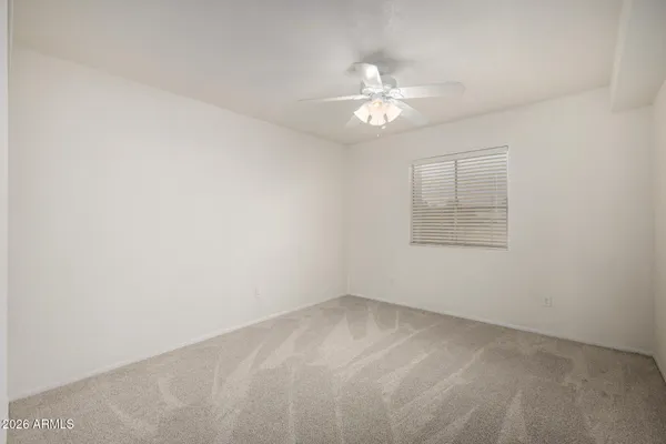 an empty room with a chandelier fan and windows