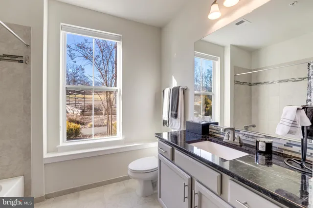 a bathroom with a granite countertop sink toilet and large mirror