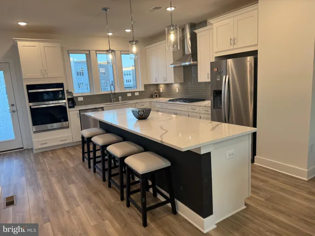 a kitchen with stainless steel appliances a table chairs refrigerator and microwave