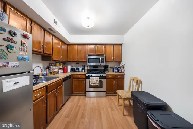 a kitchen with stainless steel appliances granite countertop a stove top oven a sink dishwasher and a refrigerator with wooden cabinets