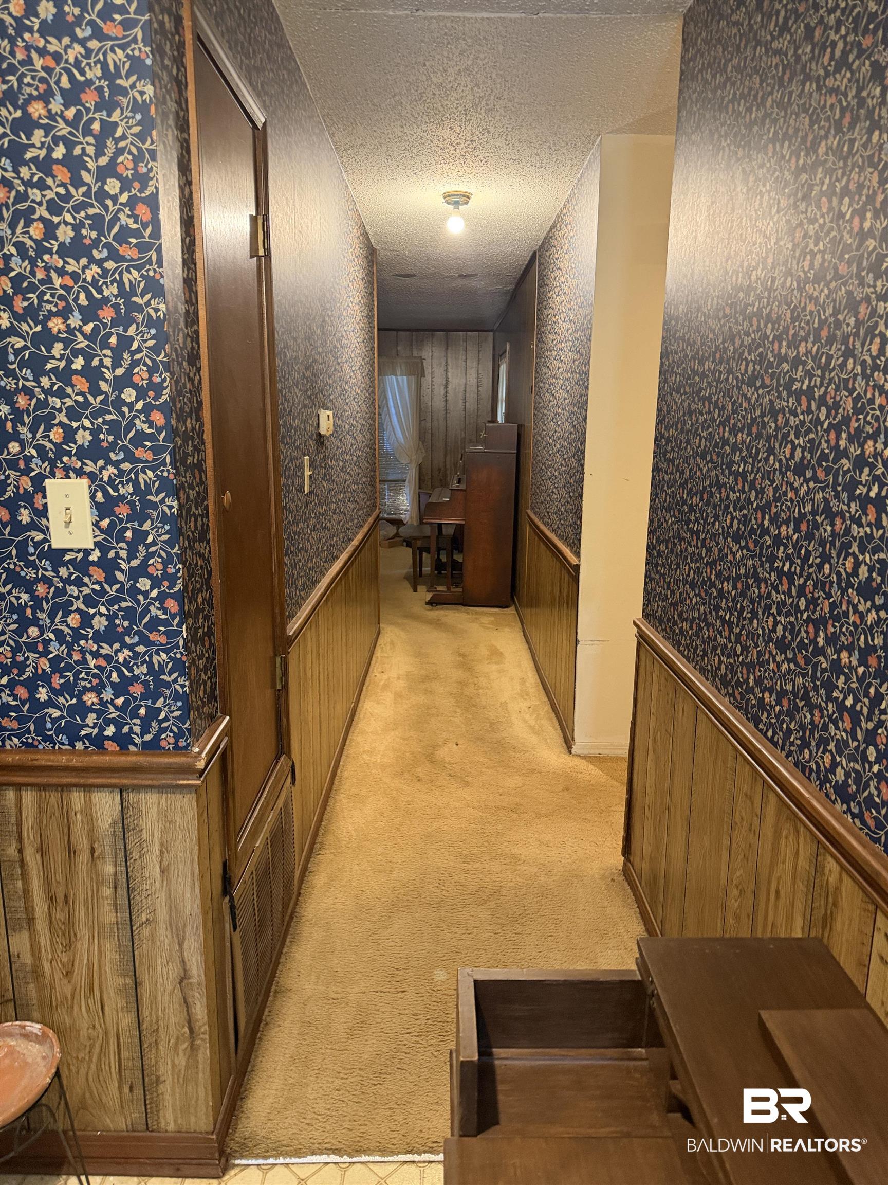 513 Club Wiley Road Jackson, AL 36545 - Photo 10 of 19 Corridor featuring a wainscoted wall, a textured ceiling, light colored carpet, wooden walls, and wallpapered walls