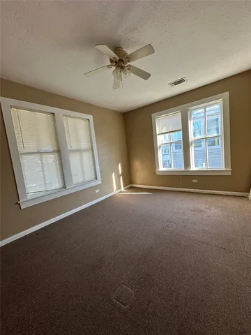 an empty room with windows and ceiling fan