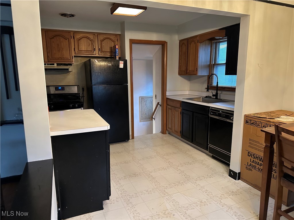 12303 Orme Road Garfield Heights, OH 44125 - Photo 2 of 22 Kitchen featuring light countertops, under cabinet range hood, a sink, visible vents, and black appliances