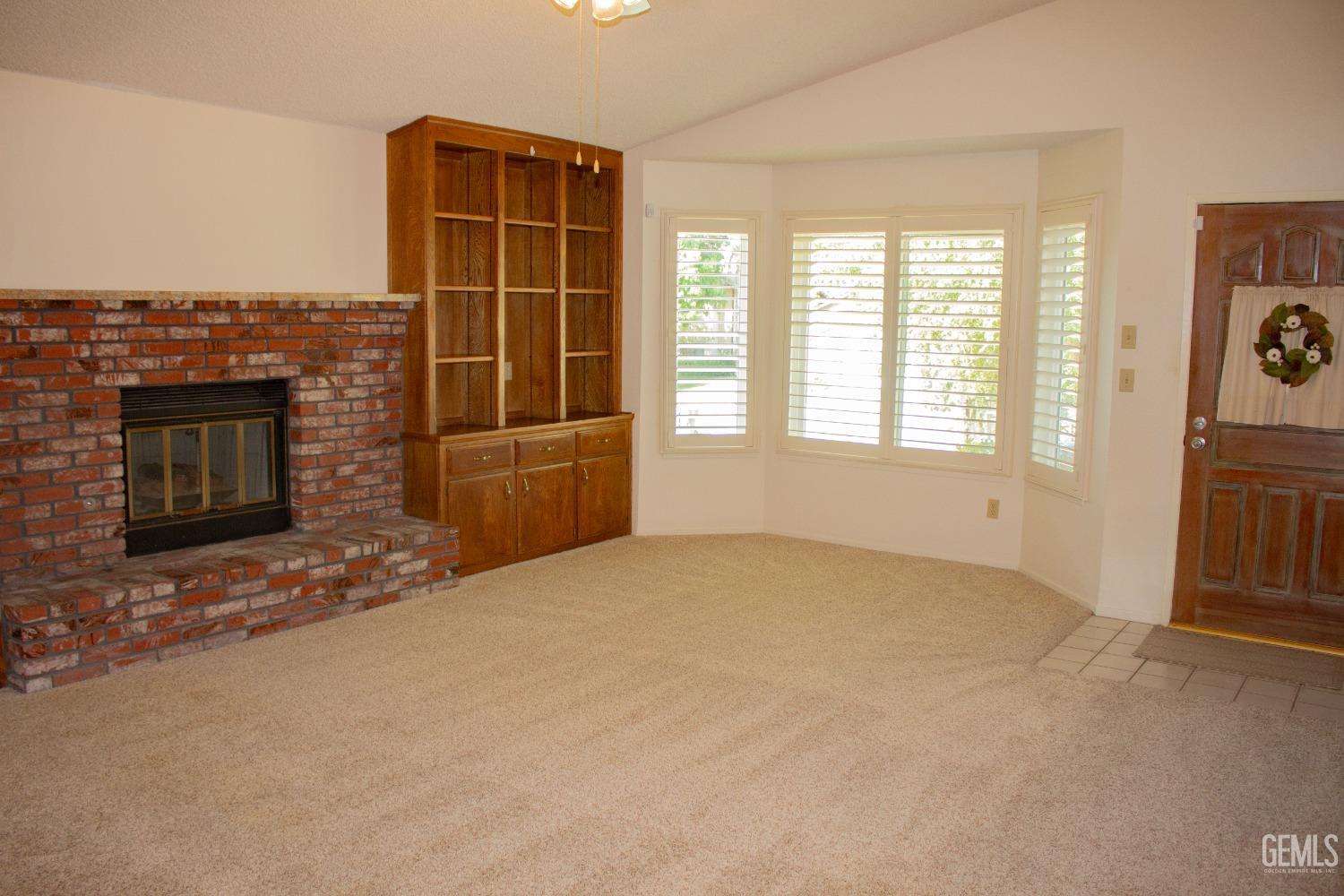 Undisclosed Address Bakersfield, CA 93306 - Photo 5 of 29 an empty room with a fireplace and windows