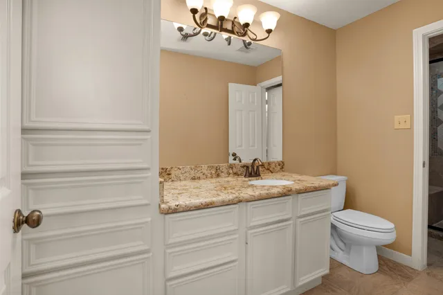 a bathroom with a granite countertop sink vanity mirror and toilet