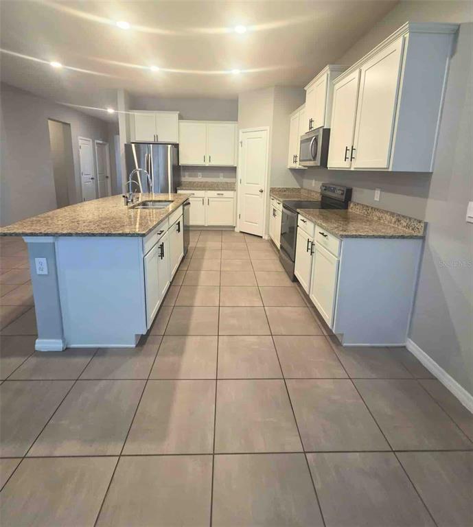 3927 Lively Coral Place Bradenton, FL 34208 - Photo 14 of 44 a large kitchen with granite countertop a stove a sink a counter space and cabinets