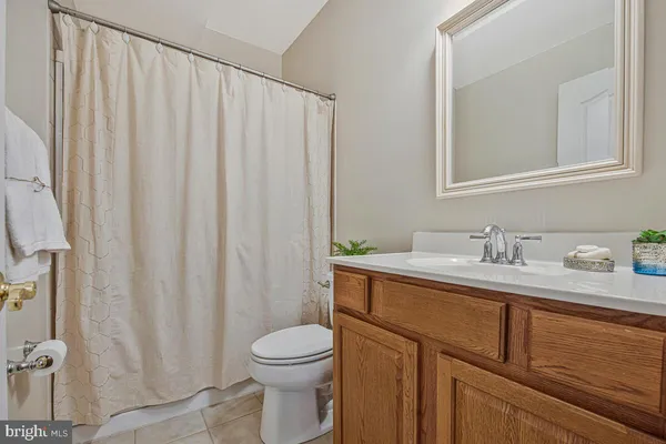 a bathroom with a granite countertop sink vanity mirror and toilet