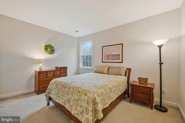 a bedroom with a bed and a lamp on dresser