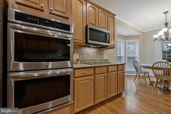 a kitchen with granite countertop wooden cabinets stainless steel appliances and wooden floor