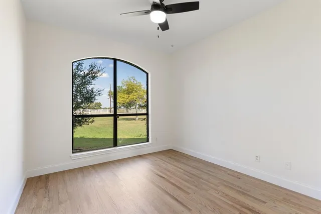 an empty room with wooden floor fan and window