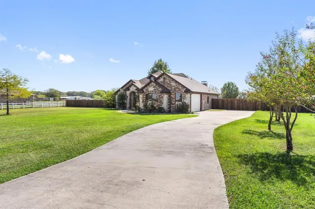 a view of a house with a big yard potted plants and large tree