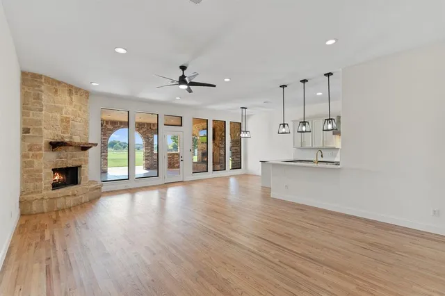 a view of an empty room with wooden floor and a fireplace