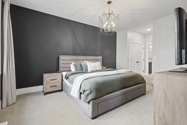 a spacious bedroom with a bed and a chandelier