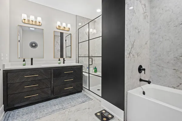 a bathroom with a tub sink double vanity and mirror