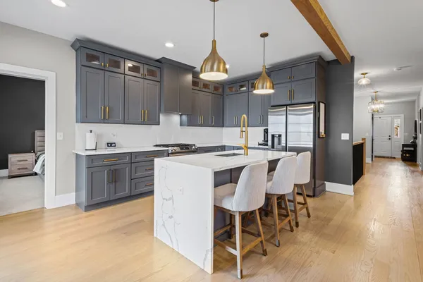 a kitchen with stainless steel appliances kitchen island granite countertop a stove a sink a refrigerator a dining table and chairs with wooden floor