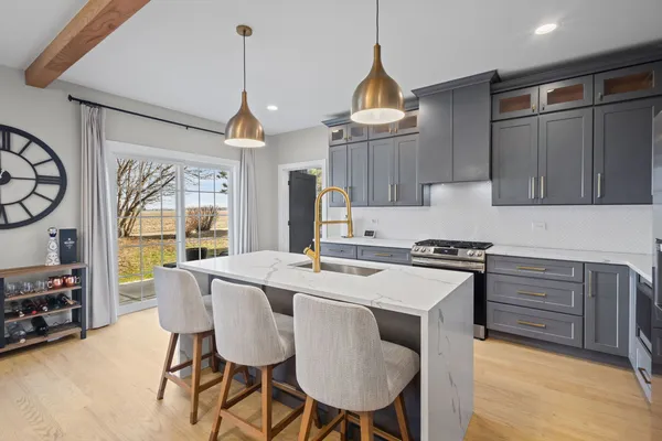 a kitchen that has a cabinets a stove a sink and a dining table with chairs