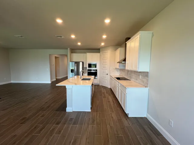 a large kitchen with wooden floor and a window