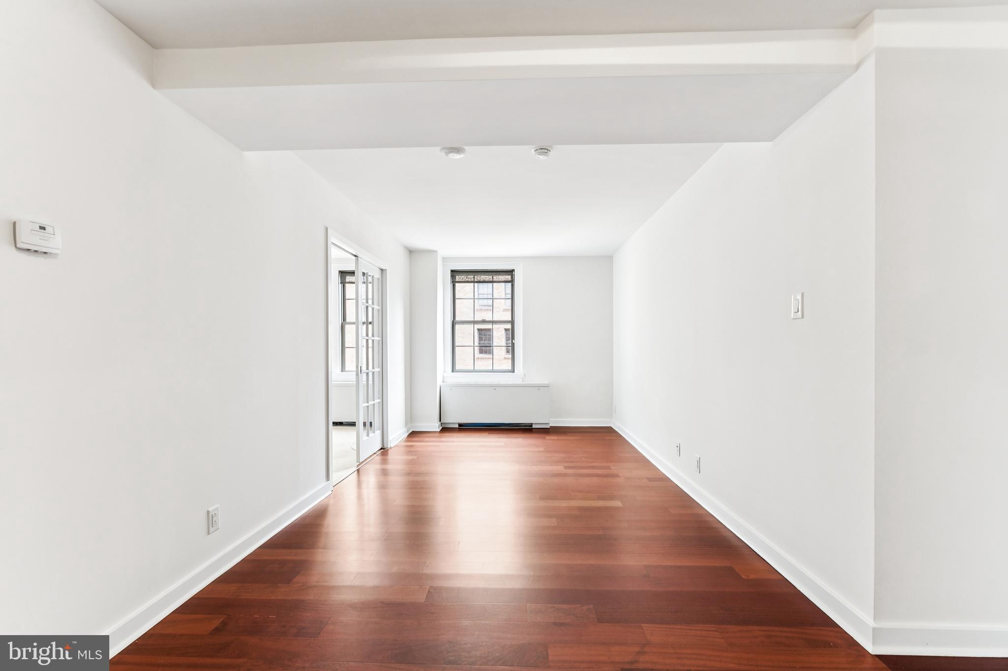 219-29 South 18th Street, Unit 1515 Philadelphia, PA 19103 - Photo 1 of 9 a view of an empty room with wooden floor and a window