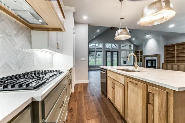 a kitchen with stainless steel appliances granite countertop a stove a sink a refrigerator and a wooden cabinets