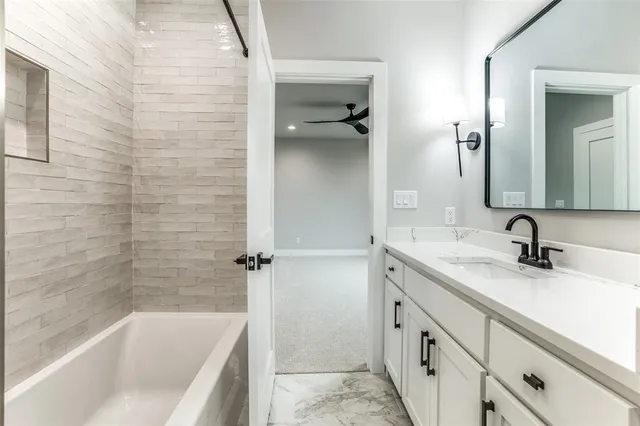 a bathroom with a granite countertop sink mirror and a bathtub