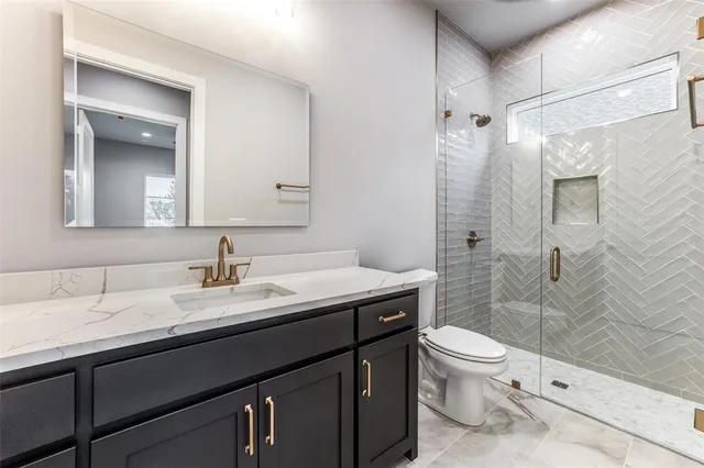 a bathroom with a granite countertop sink a toilet and shower