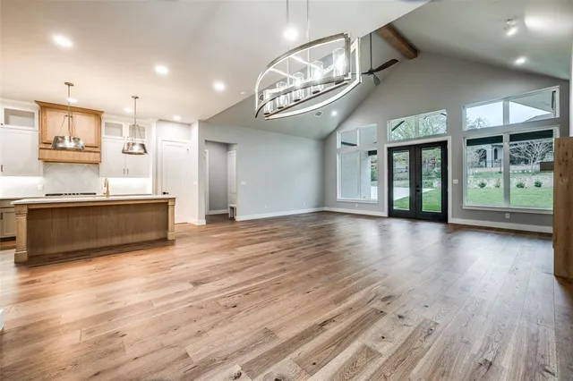 an empty room with wooden floor and a kitchen view