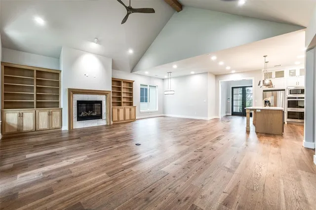 an empty room with wooden floor fireplace and windows