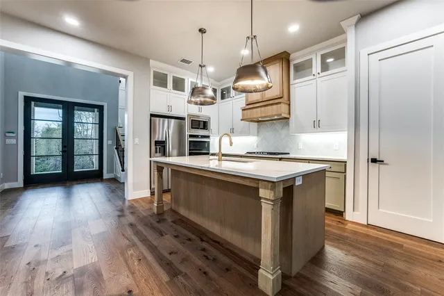 a kitchen with stainless steel appliances granite countertop a refrigerator a stove and a wooden floors