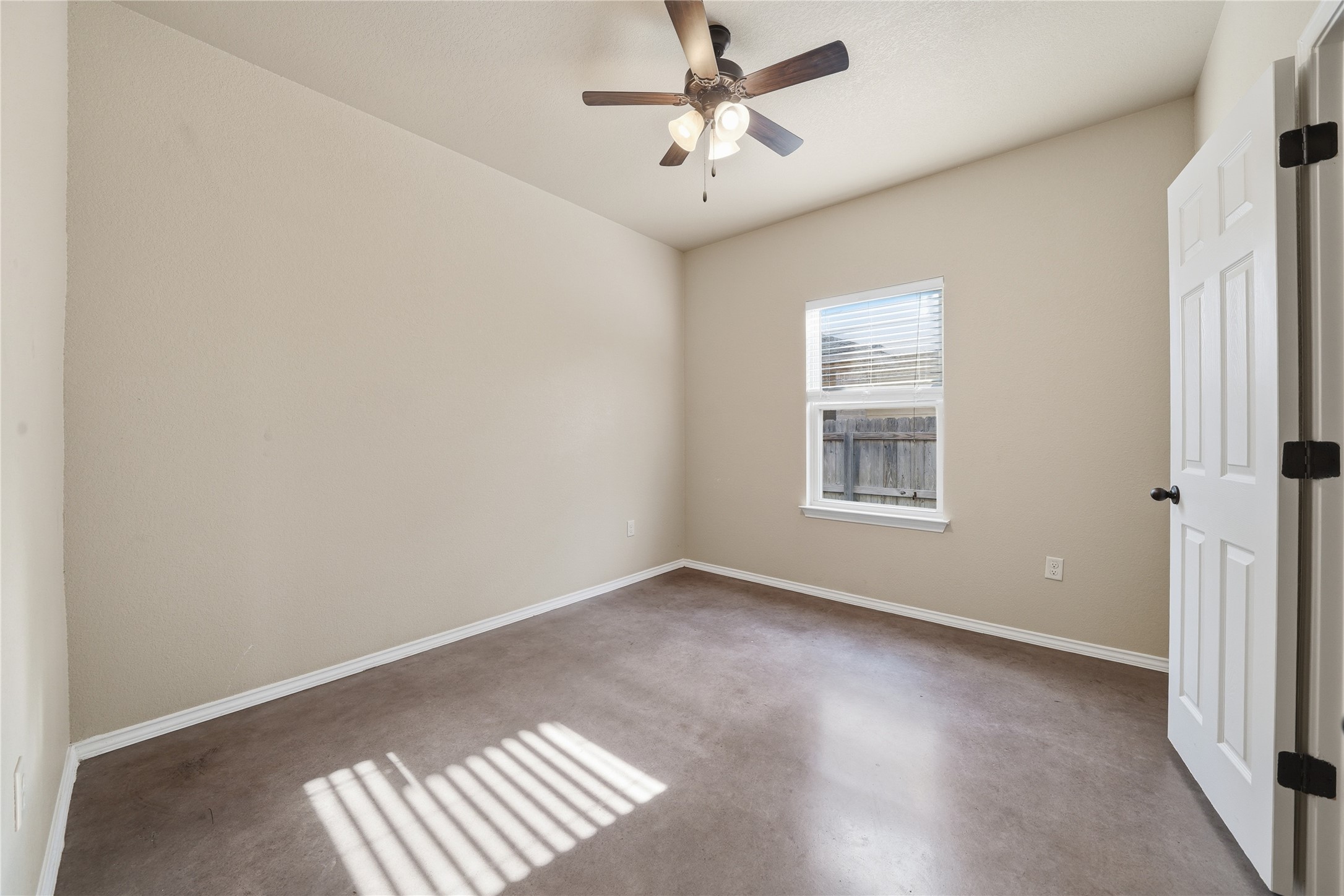 533 Jack Rabbit Lane, Unit A Buda, TX 78610 - Photo 18 of 34 A well-lit bedroom features a vaulted ceiling with a fan and durable concrete flooring.
