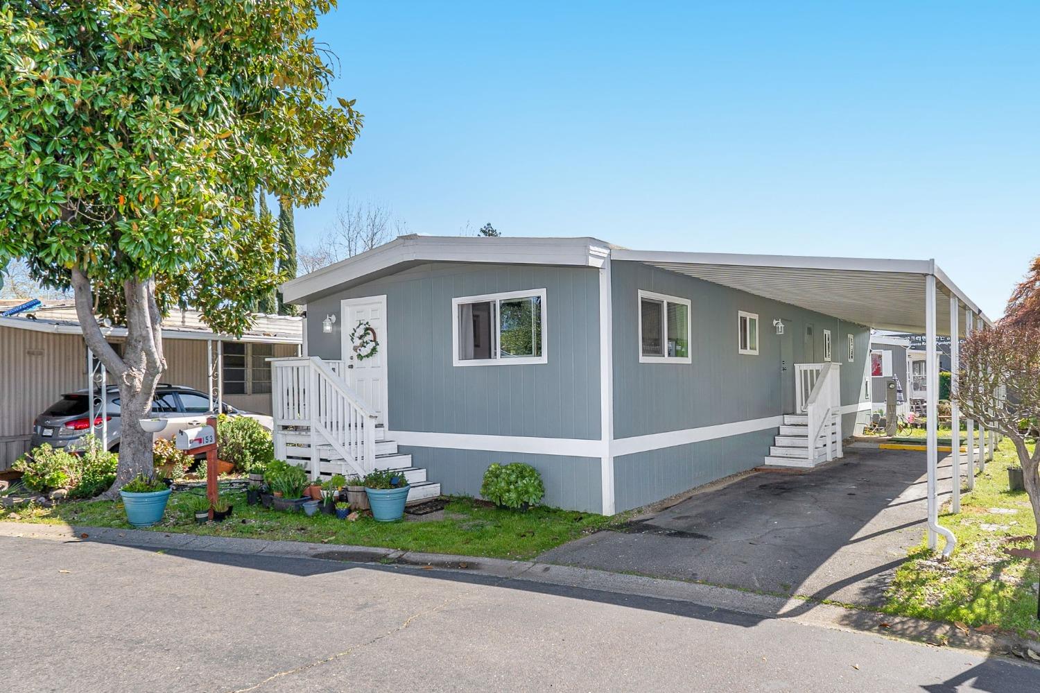 10035 Mills Station Road, Unit 153 Sacramento, CA 95827 - Photo 1 of 23 a front view of a house with a yard and potted plants