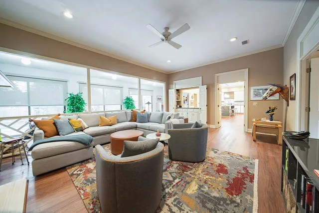 a living room with furniture potted plant floor to ceiling windows and a ceiling fan