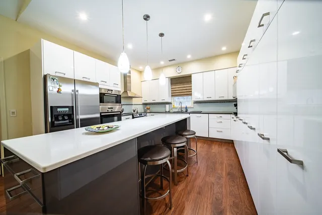a large kitchen with a table chairs sink and wooden floor