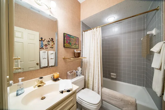 a bathroom with a bathtub shower sink vanity mirror and toilet
