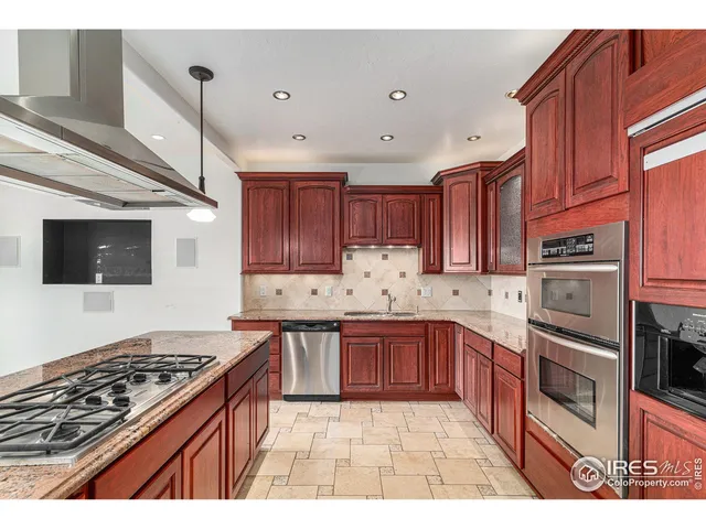 a kitchen with stainless steel appliances granite countertop a stove top oven a sink dishwasher and cabinets with wooden floor