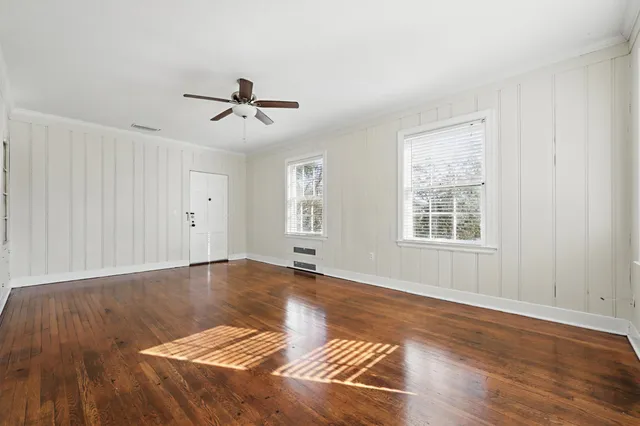an empty room with wooden floor ceiling fan and windows